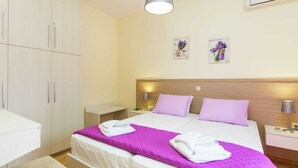 A hotel room with a bed, nightstands, a wardrobe, and an air conditioning unit. - Small Apartmentcomplex in Village of Prinès near Rethymnon (Rethymno)