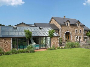 Una casa moderna con veranda in vetro, rivestimento in pietra e prato curato.
