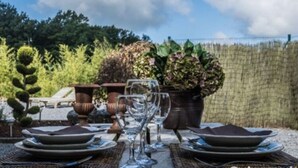 An outdoor dining area with a table set for two, surrounded by lush greenery and a decorative urn. - Luxury Spa Retreat in Theux (Theux)