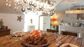 A dining area with a wooden table set for a meal, a hanging light fixture above, and a kitchen in the background. - Luxury Spa Retreat in Theux (Theux)