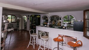 A bar area with white bar stools, a bar counter, and a large metal sculpture. - Belvilla by OYO Casa Rosa (Terranuova Bracciolini)