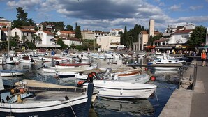 Un port de plaisance où sont amarrés différents types de bateaux, entouré de bâtiments et sous un ciel dégagé.
