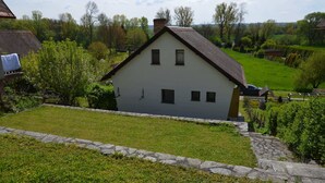 A single-story house with a sloped roof, a stone pathway leading to the front door, and a well-maintained lawn.