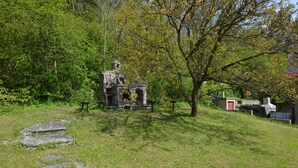 A stone structure with a chimney, surrounded by grass and trees.