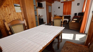 A dining area with a long wooden table, chairs, and a sofa.