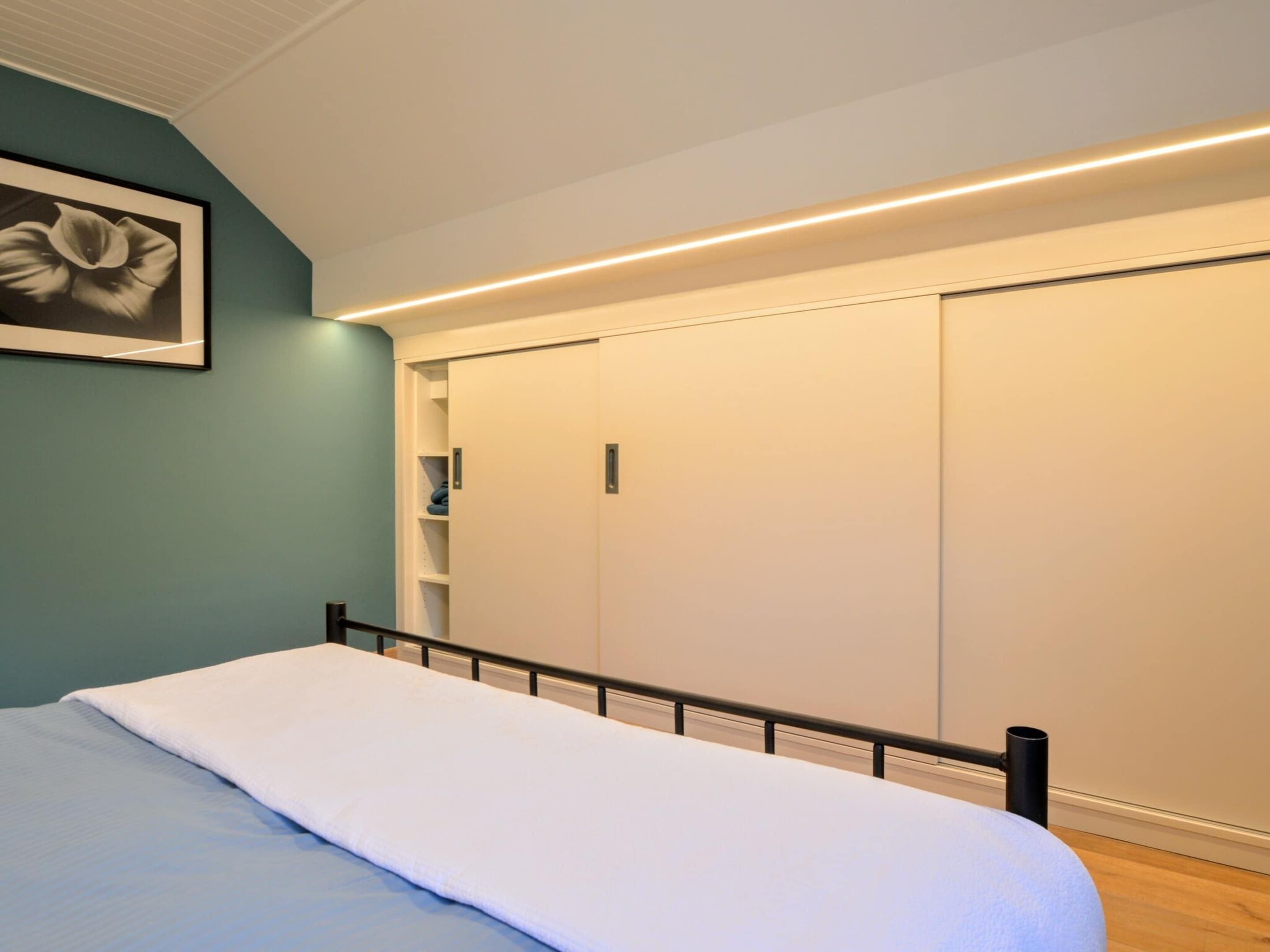 Une chambre à coucher avec un lit, une armoire et un tableau encadré au mur.