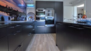 Une cuisine moderne dotée d’appareils électroménagers intégrés, d’un grand îlot central et d’une fresque murale décorative.