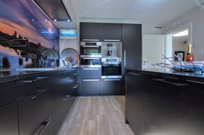 A modern kitchen with built-in appliances, a large island, and a decorative wall mural. - Elsenborn Retreat Near Monschau (Buetgenbach)