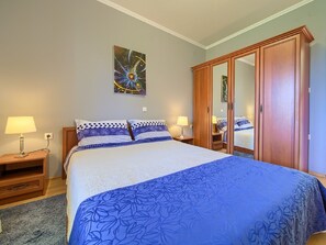 A bedroom with a large bed, two bedside tables with lamps, a wardrobe, and a wall painting. - Pleasant Apartment in Vantacici Amid the Sea (Malinska-Dubasnica)