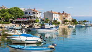 A marina with several boats docked, surrounded by buildings with red-tiled roofs and balconies. - Pleasant Apartment in Vantacici Amid the Sea (Malinska-Dubasnica)