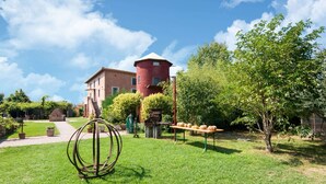 Un patio con una torre roja, una escultura de metal y una mesa con calabazas.