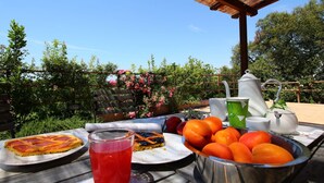 An outdoor dining table with plates of food, a drink, and a bowl of fruit. - Farmhouse in Montalto Near Sandy Beach (Montalto di Castro)