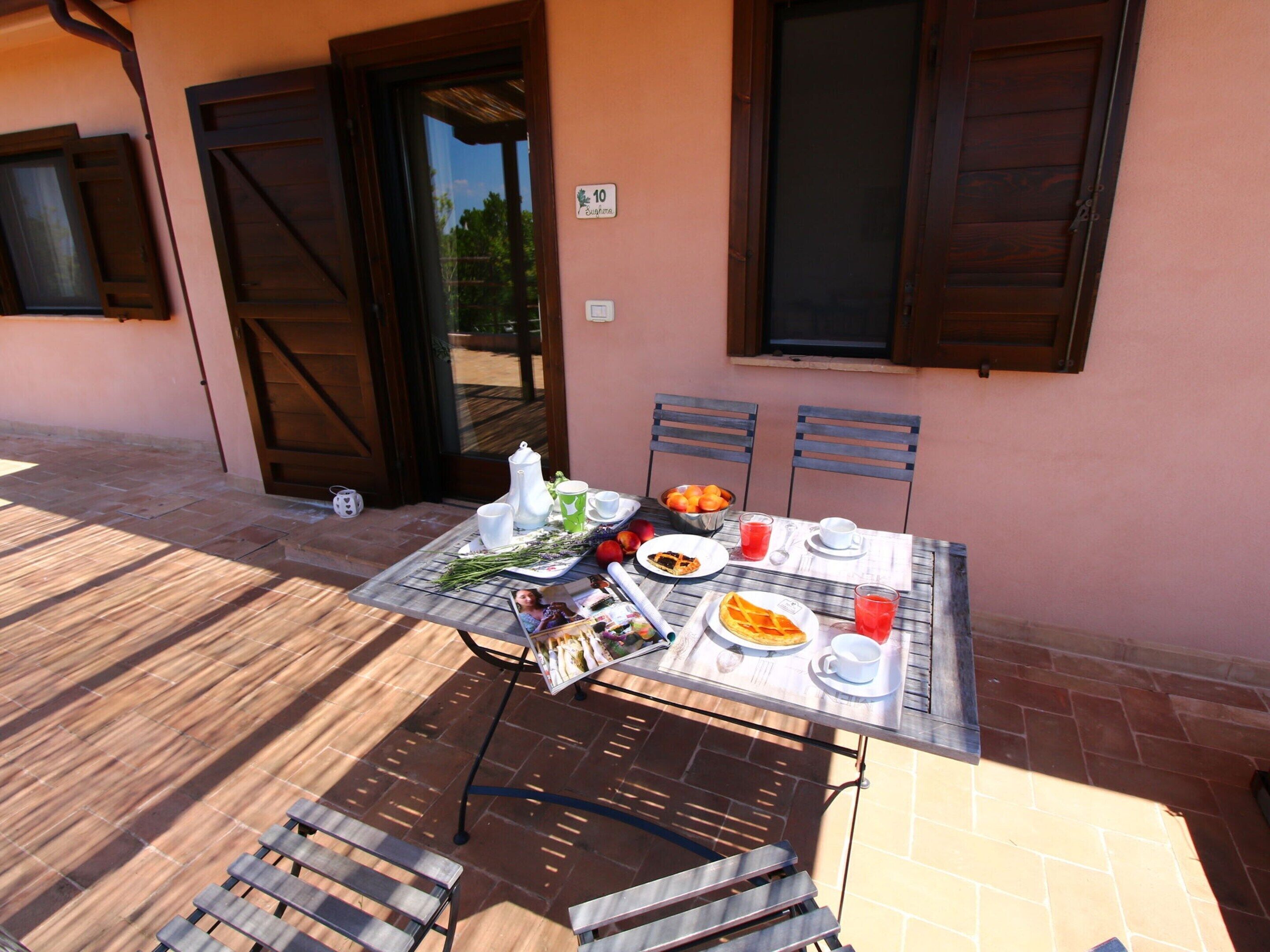 Un espacio exterior para comer con una mesa lista para dos personas, que presenta una variedad de platos y bebidas.