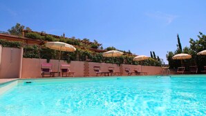 A swimming pool with clear blue water, surrounded by lounge chairs and umbrellas. - Farmhouse in Montalto Near Sandy Beach (Montalto di Castro)