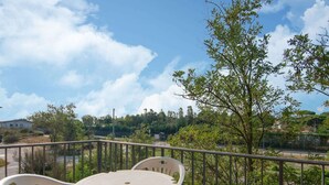 A balcony with a table and chairs, overlooking a road and greenery. - Loving Apartment in Rosolina Mare near Venice (Rosolina)