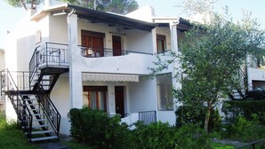 A two-story building with a balcony, a staircase, and a garden area. - Simplistic Apartment in Rosolina Mare near Sea (Rosolina)