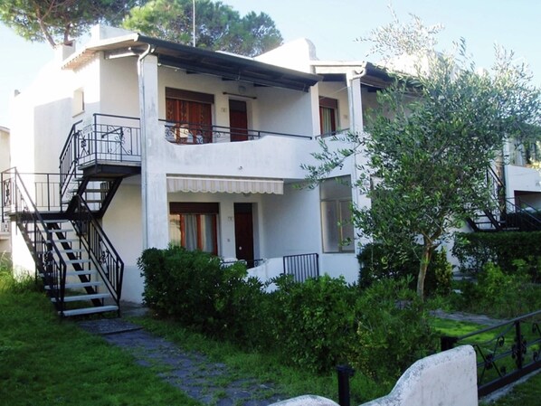 A two-story building with a balcony, a staircase, and a garden area. - Simplistic Apartment in Rosolina Mare near Sea (Rosolina)