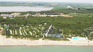 An aerial view of a coastal resort with a beach, dense greenery, and a large body of water. - Simplistic Apartment in Rosolina Mare near Sea (Rosolina)