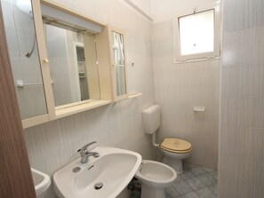 A bathroom with a sink, bidet, toilet, and a mirror. - Simplistic Apartment in Rosolina Mare near Sea (Rosolina)