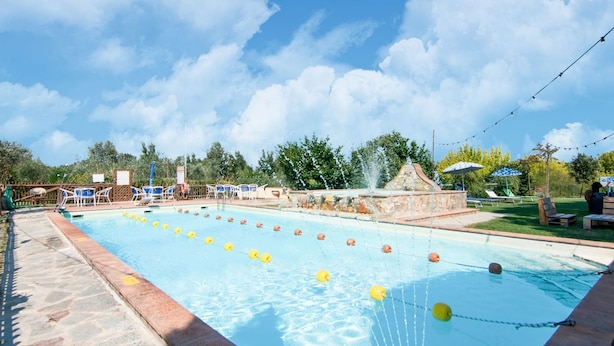 En swimmingpool med banmarkeringar, solstolar och en fontän.
