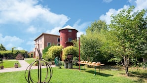 En innergård med en skulptur i metall, ett bord med pumpor och en röd tornbyggnad i bakgrunden.