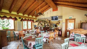 Ein Restaurant mit Holzbalken, Fliesenboden und Tischen mit rot-weißen Tischdecken.