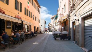 Eine schmale Straße gesäumt von Cafés und Restaurants, mit Außenplätzen und wenigen Passanten.