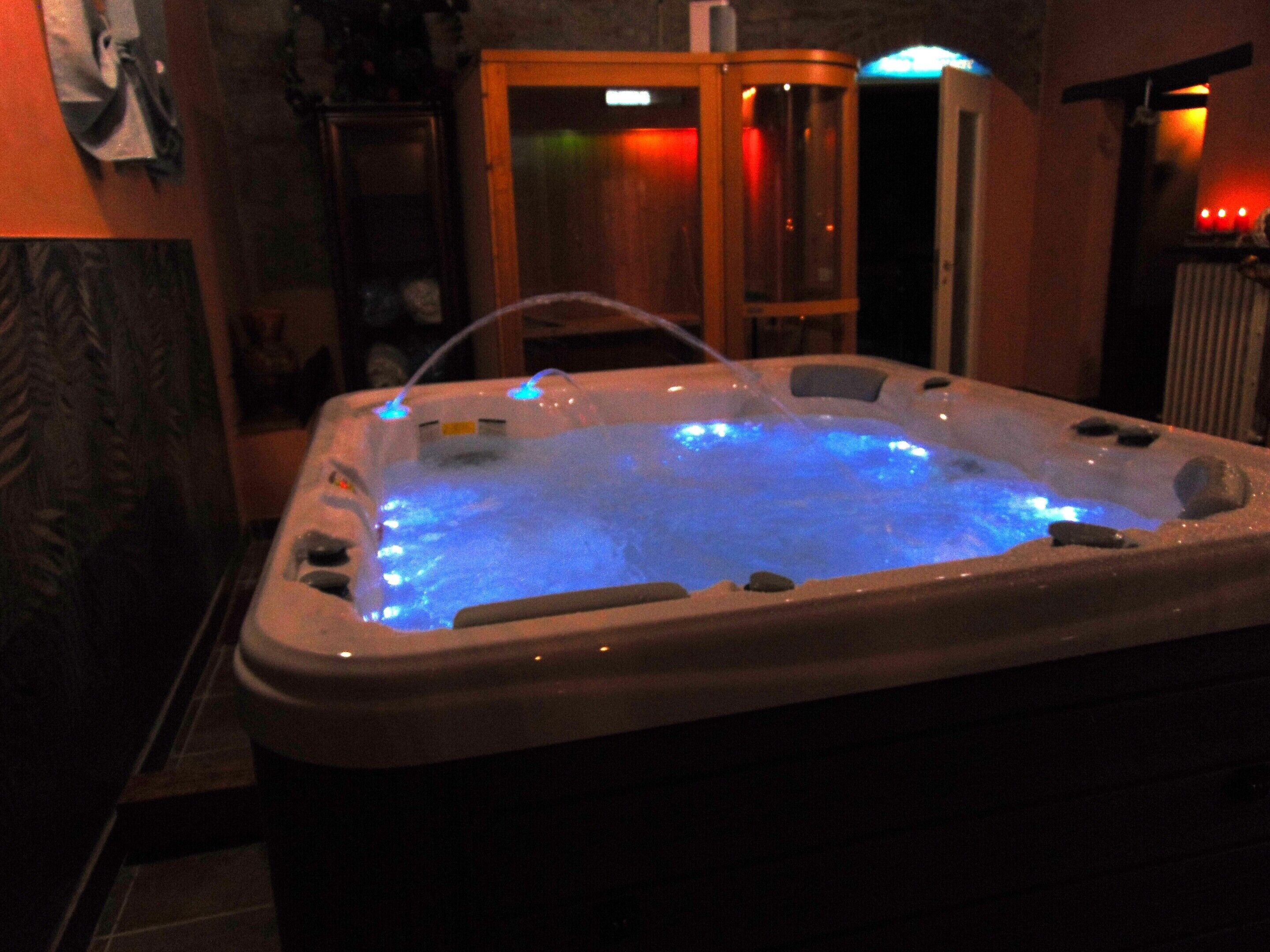 Un bain à remous avec un éclairage bleu, un meuble en bois et un sol carrelé.