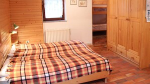 A wooden-paneled room with a bed, a radiator, a window with curtains, and a wardrobe. - Balmy Apartment in Bohinjsko Jezero near Lake (Bohinj)