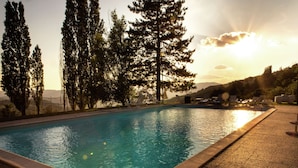 A rectangular swimming pool with clear blue water, surrounded by a pebble deck.
