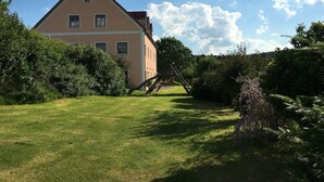 A two-story building with a sloped roof, surrounded by a well-maintained lawn and dense shrubbery. - Schonsee Forest Escape (Schoensee)