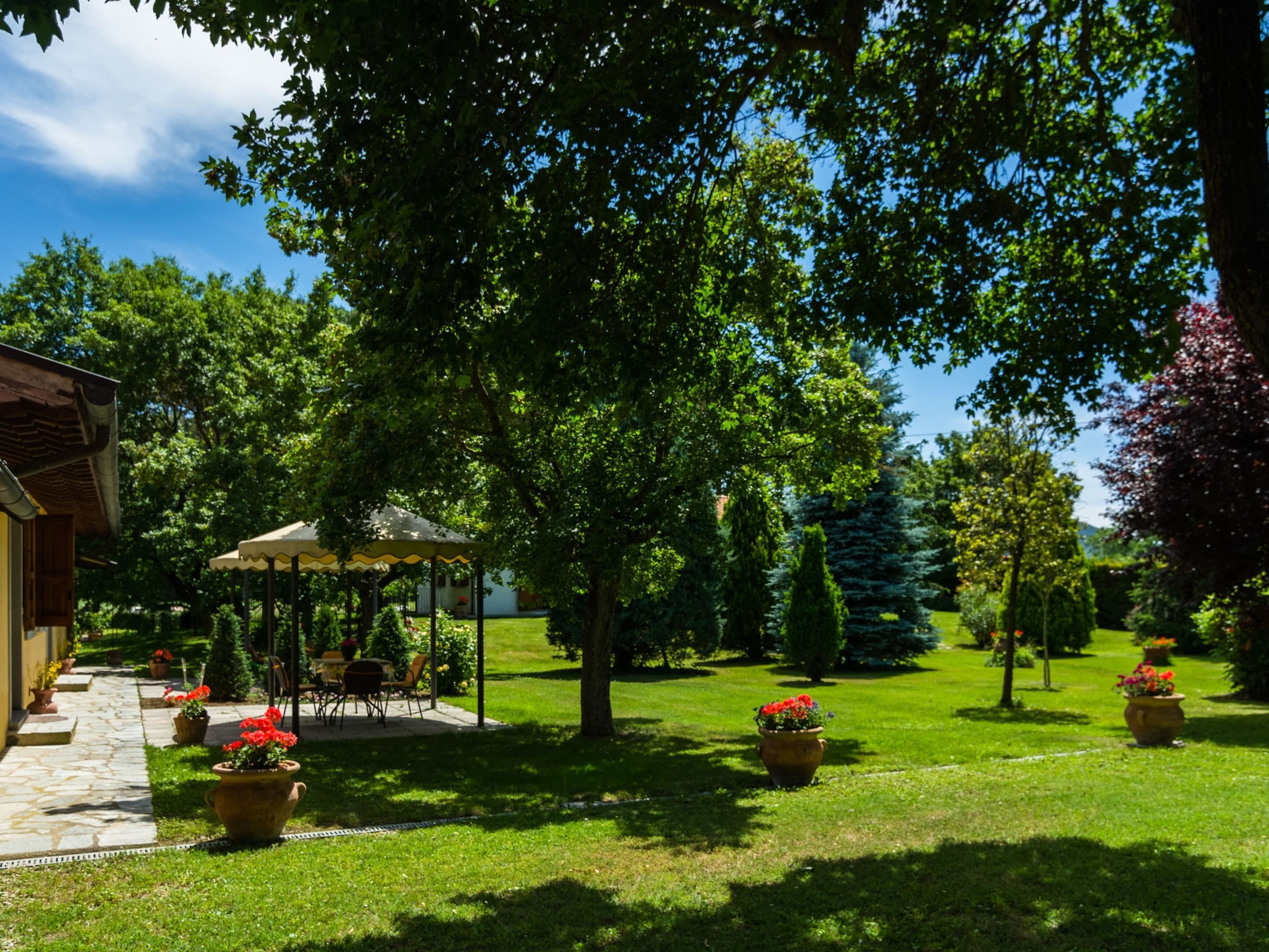Ein Garten mit einem Pavillon, Blumentöpfen und einem gepflasterten Weg.