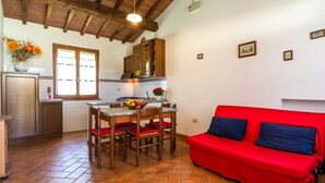 Una cucina accogliente con un divano rosso, mobili in legno e pavimento piastrellato.