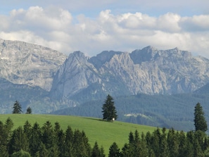 Un paysage montagneux avec une colline herbeuse et un petit bâtiment.