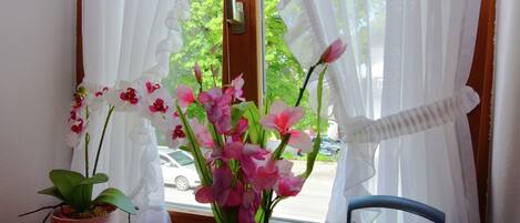A window with sheer curtains, a potted plant, and a radio on a windowsill.