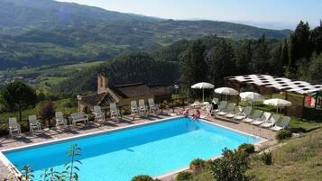 Relax by the serene pool surrounded by lush green hills and comfortable lounge chairs.