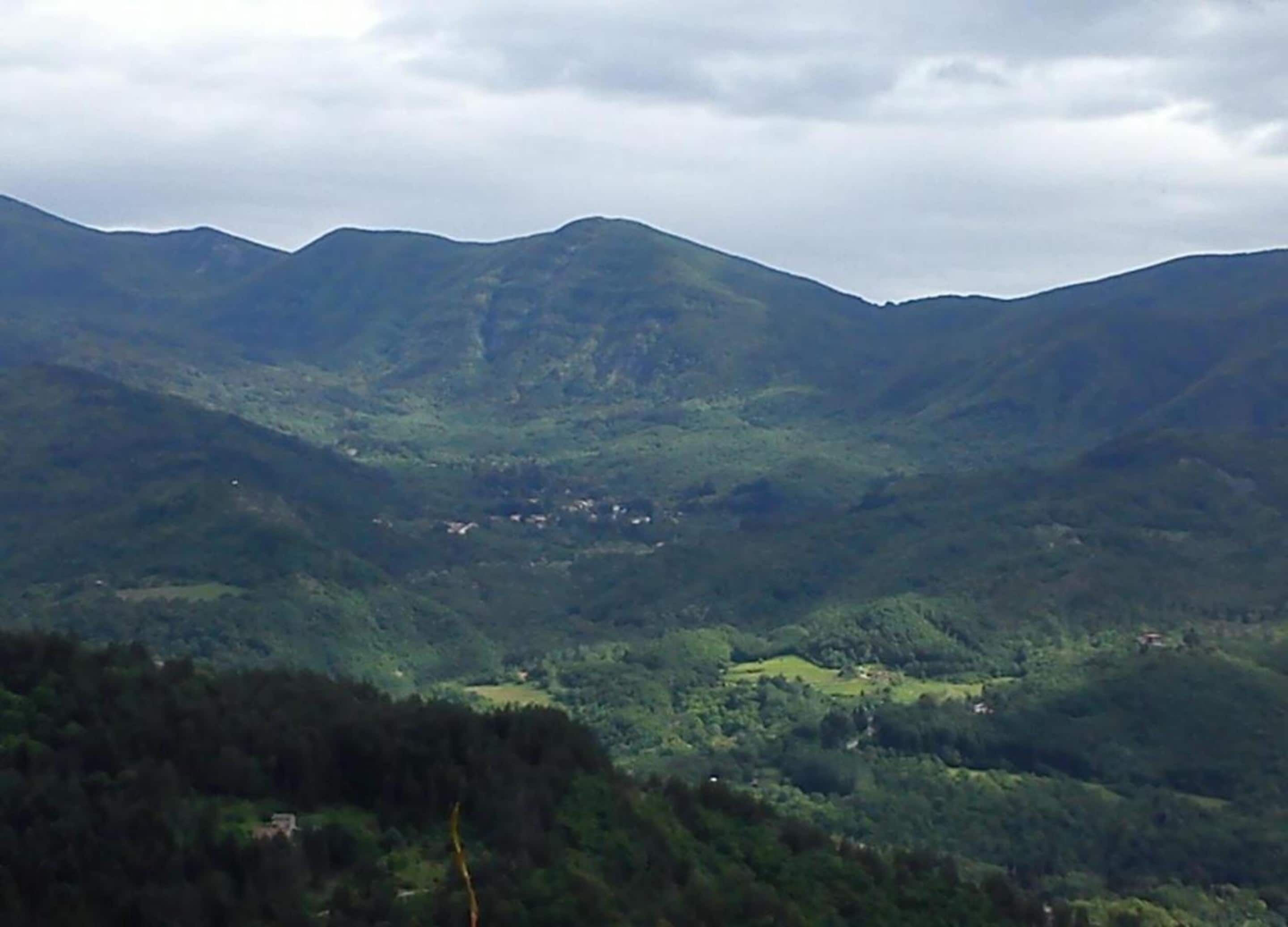Paesaggio montuoso con una valle e edifici sparsi.