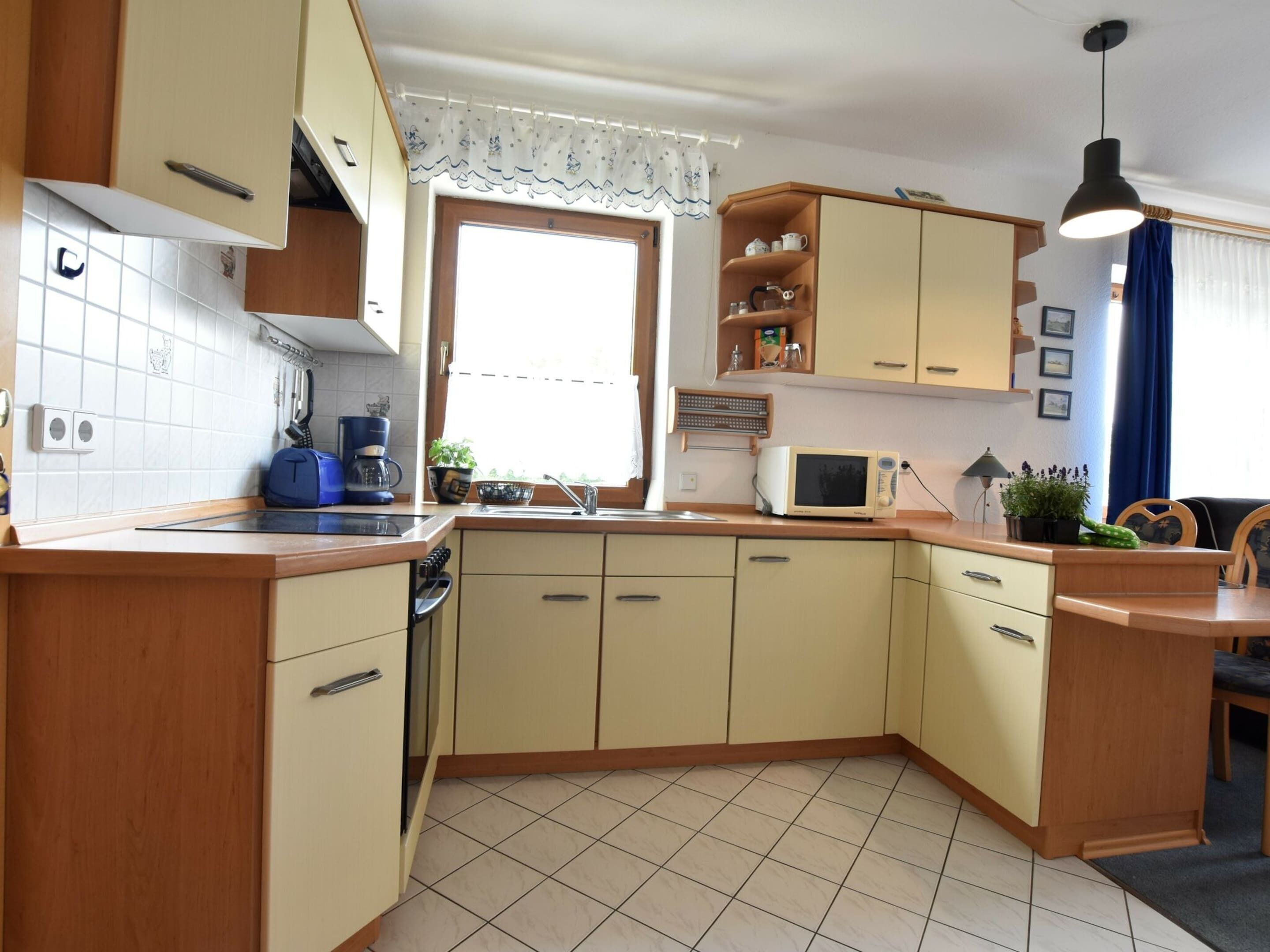 A compact kitchen with wooden cabinets, a microwave, a coffee maker, and a sink.