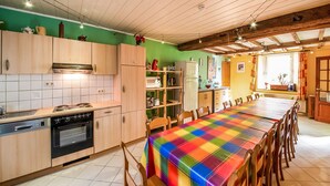 A kitchen with wooden cabinets, a dining table with a colorful tablecloth, and a view of the outside through a window.