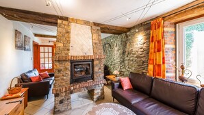A cozy living room with a stone fireplace, leather sofas, and a patterned table.