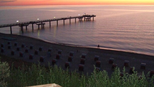 Um píer se estendendo sobre águas calmas ao pôr do sol.