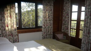 Une chambre avec un grand lit, une chaise et une vue sur l’extérieur par une fenêtre.