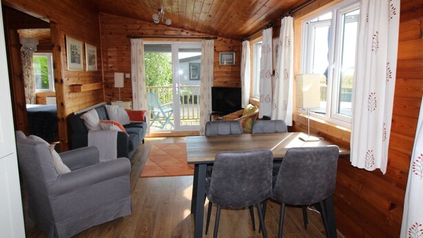 Un intérieur de chalet chaleureux avec un canapé, une table à manger et des chaises.