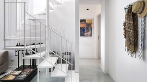 A modern interior with a white staircase, a sofa, a coffee table, and a wall-mounted hat rack. - Apartment Near the Sea and the Center of San Vito lo Capo (San Vito Lo Capo)