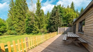 A wooden deck with picnic tables, surrounded by a wooden fence and dense forest. - Mansion With Pool & Bar (Buellingen)