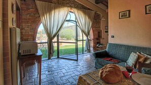 A cozy room with a stone wall, a wooden table with a loaf of bread, a glass of red wine, and a blue sofa. - Cottage in Todi With Pool and Terrace (Todi)