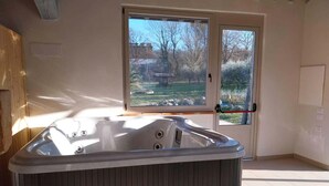 A modern bathroom with a freestanding bathtub, a large window with a view of a garden, and a wooden ceiling. - Cottage in Todi With Pool and Terrace (Todi)