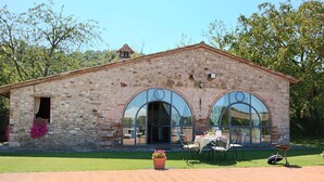 A stone building with arched windows and a brick patio. - Cottage in Todi With Pool and Terrace (Todi)