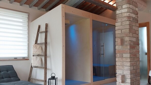 A room with a glass partition, a wooden ladder, a wicker chair, and a lantern. - Cottage in Todi With Pool and Terrace (Todi)