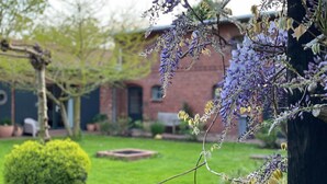 Un giardino con un edificio in mattoni, un prato verde e un cespuglio.